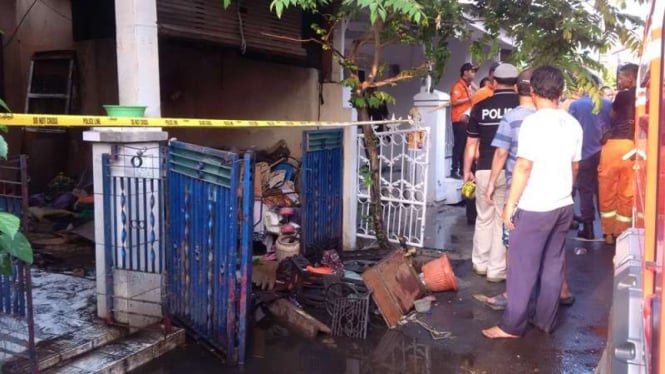 Polisi membentangkan garis polisi di depan rumah korban kebakaran di Bekasi.