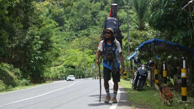 Safir dan anjingnya Batu, berjalan kaki di ruas jalan Gunung Parau Aceh Besar, Kamis (31/8/2017). Sebelas bulan sudah Safir berjalan kaki menyusur Pulau Sumatera. 