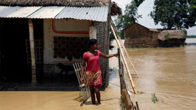 Seorang gadis berdiri di depan rumahnya yang banjir di Nepal.