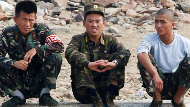 Para prajurit Korea Utara duduk di tepi sungai Yalu