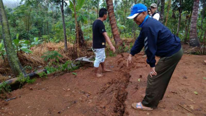 Sekretaris Kecamatan Cisompet, Nurbani Tamim menunjukkan tanah retak 