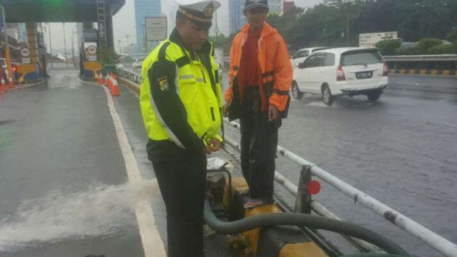Petugas tengah melakukan penyedotan air di tol Pancoran arah Semanggi
