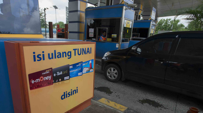 Pengguna jalan tol melintas di samping gardu tol yang melayani pengisian ulang e-Money Mandiri di Gerbang Tol Cililitan, Jakarta, Selasa, 10 Februari 2017. 