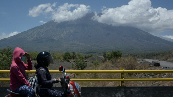 Warga melintas di kawasan Kubu yang berjarak sekitar 12 kilometer dari Gunung Agung di Karangasem, Bali, Sabtu (14/10). 