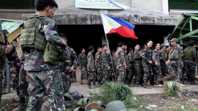 Militer Filipina mengibarkan bendera Filipina di kota Marawi.