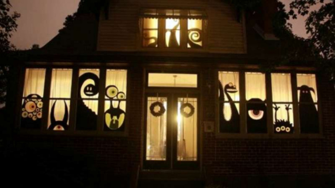 Dekorasi rumah halloween dengan monster menempel di jendela 