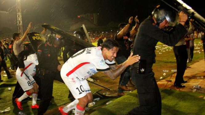 Pemain Bali United, Irfan Bachdim, berlindung dari lemparan suporter PSM.