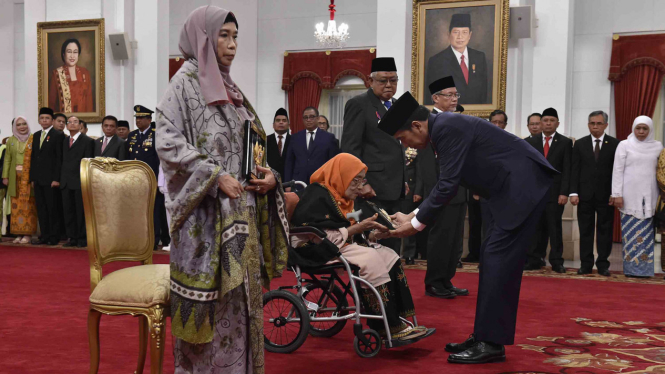 Presiden Jokowi saat memberikan surat keputusan penetapan pahlawan nasional kepada keluarga yang berhak di Istana Negara, 9 November 2017.