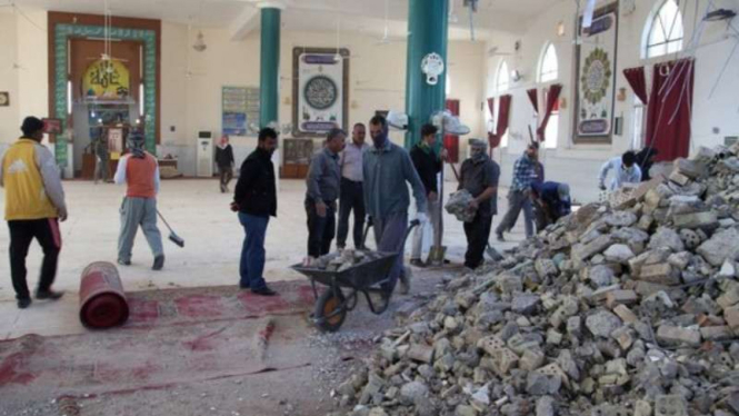 Warga Iran membersihkan puing yang berjatuhan akibat gempa dari dalam masjid.