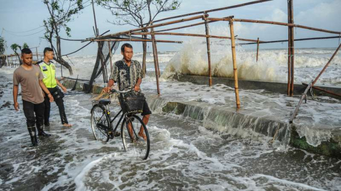 Sejumlah warga menghindari gelombang laut yang mengenai garis pantai di Pantaisari, Pekalongan, Jawa Tengah, Jumat (1/12/2017).