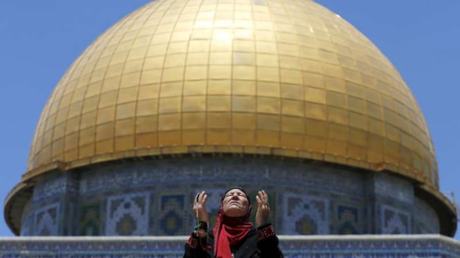 Seorang perempuan warga Palestina berdoa dengan latar Kubah Shakrah atau Dome of the Rock di Yerusalem.
