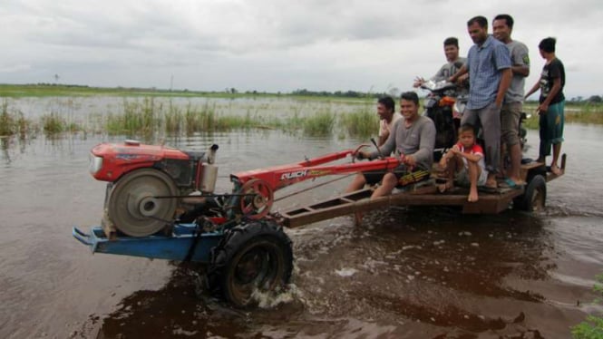 Sejumlah warga di Aceh Utara mencoba melintasi genangan air yang merendam wilayah itu, Kamis (7/12/2017)