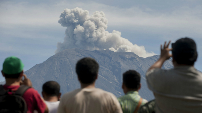 Sejumlah warga menyaksikan asap disertai abu vulkanis keluar dari kawah Gunung Agung yang masih berstatus awas, di Pos Pengamatan Gunung Api Agung, Desa Rendang, Karangasem, Bali, Sabtu (9/12). 
