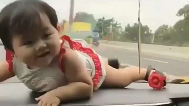 Bayi ditaruh di atas dasbor mobil.