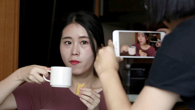 Seorang wanita tengah di rekam menggunakan smartphone saat mencoba sebuah makanan di Hongkong, Cina.