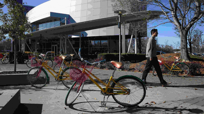 Serorang melintas di antara sepeda Google di markas pusat Google