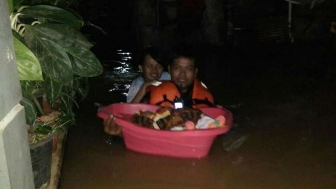 Korban banjir di Jakarta Timur membawa bayi mereka ke tempat aman.