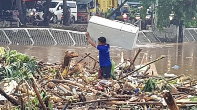 Pemulung membawa kulkas yang ditemukan di Kali Ciliwung.