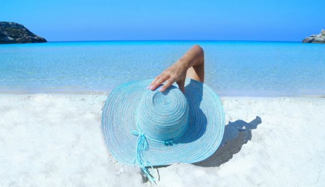 Wanita mengenakan topi biru di pantai