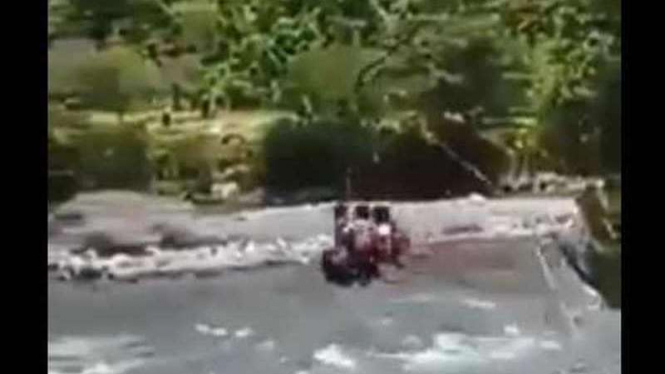 Tiga anak sekolah menyeberangi sungai pakai seluncuran.