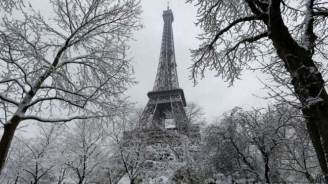 Menara Eiffel dan pepohonan yang tertutup salju di Prancis.
