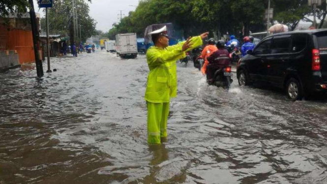 Petugas mengatur lalu lintas imbas banjir depan Samsat Jakarta Barat.