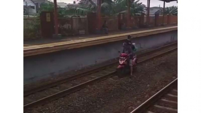 Sepeda motor melewati jalur kereta api.