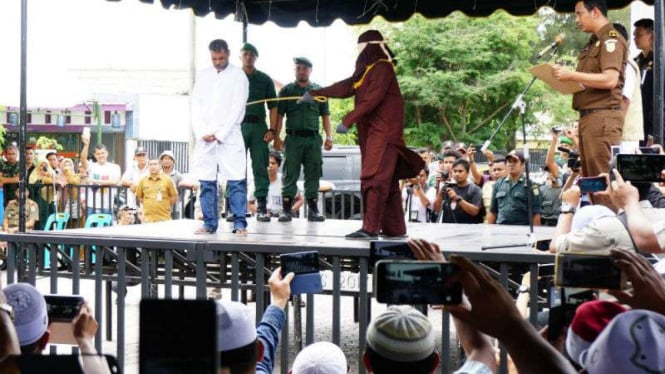 Serombongan turis asal Malaysia mengabadikan momen hukuman cambuk menggunakan kamera ponsel di Kota Banda Aceh pada Selasa, 27 Februari 2018.