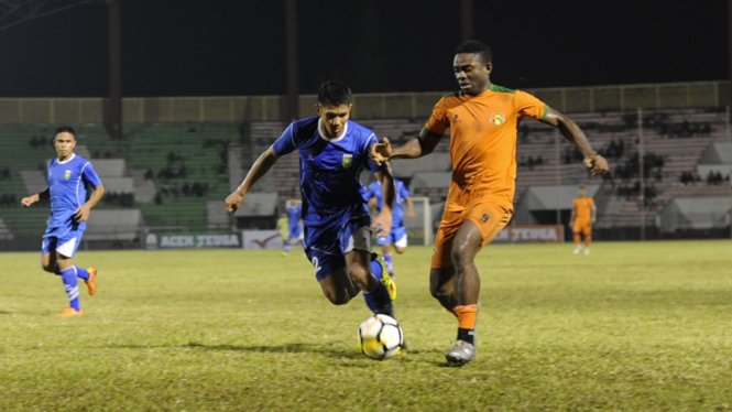 Pemain naturalisasi Aceh United, Osas Saha berduel dengan pemain PSPS Riau.
