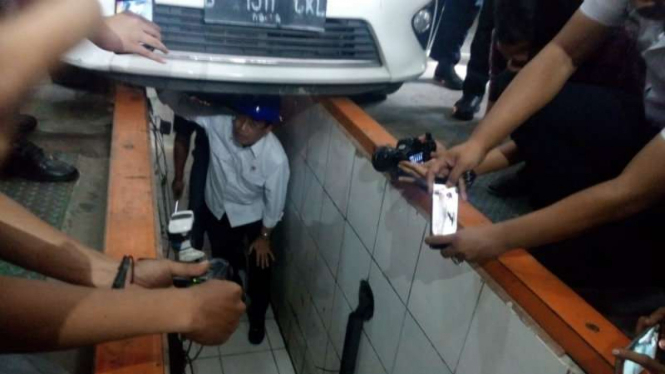 Menteri Perhubungan Budi Karya Sumadi saat mengecek suatu kendaraan dari bawah.