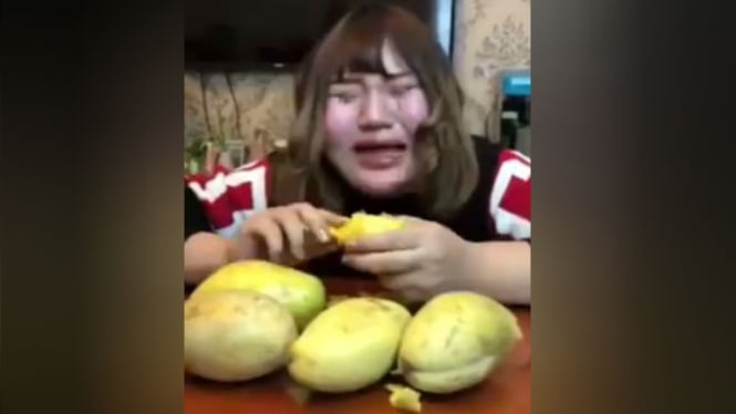 Wanita menangis saat memakan mangga.