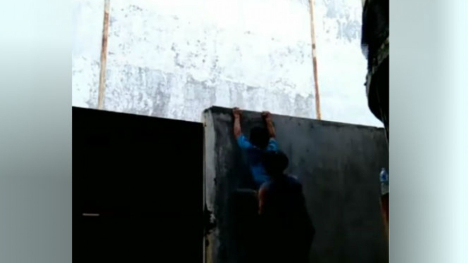 Dua pria mencoba memanjat tembok.