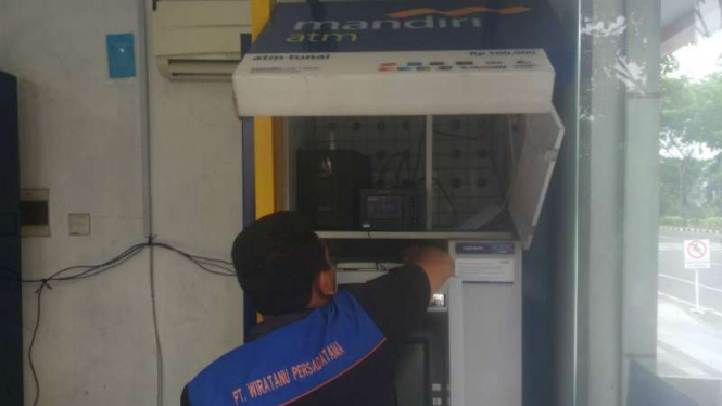 Petugas memeriksa ATM Mandiri di halaman Graha Pena Surabaya pada Senin, 19 Maret 2018.