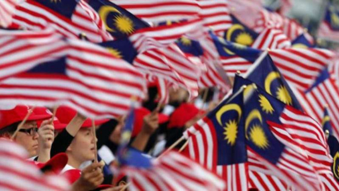 Rakyat Malaysia mengibarkan bendera nasional. 