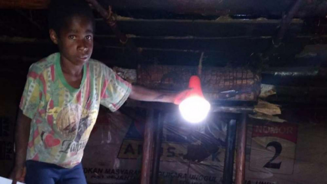 Seorang anak di pedalaman Papua dapat penerangan listrik.