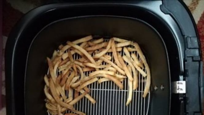 Air fryer dan sisa kentang goreng di dalamnya.