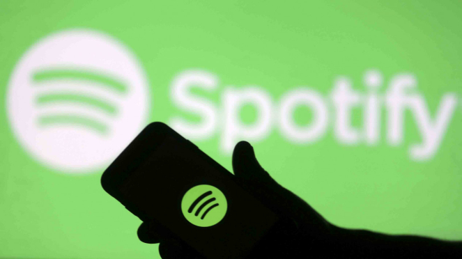 Sebuah smartphone berada di depan layar proyektor logo Spotify