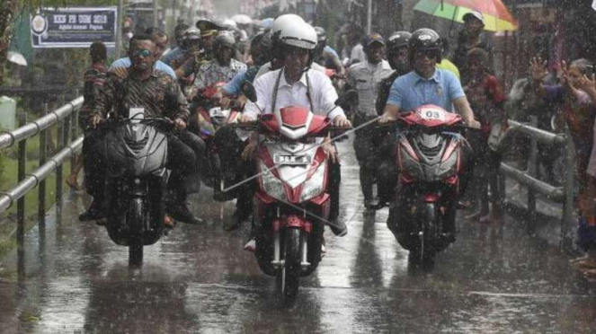Jokowi bersama istri hujan-hujanan naik motor listrik di Papua.