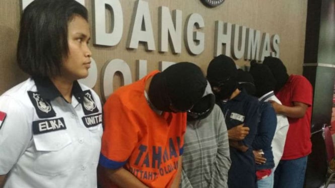 Pasangan suami-istri (berpenutup kepala) yang digerebek saat berpesta seks bebas dan tukar pasangan diperlihatkan di Markas Polda Jatim, Surabaya, pada Senin, 16 April 2018.