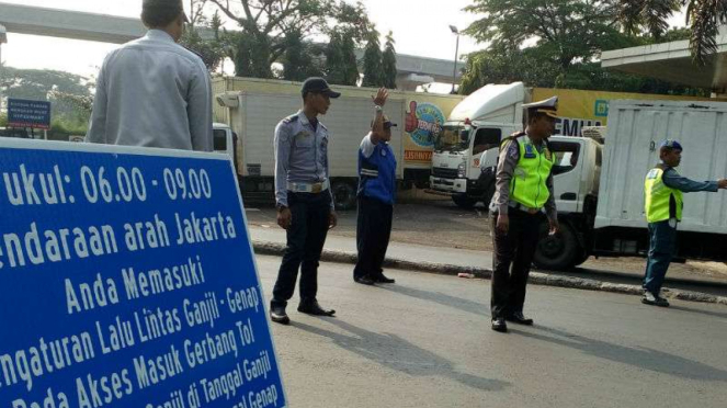 Petugas mengawasi penerapan sistem ganjil genap di depan gerbang Tol Cibubur II 