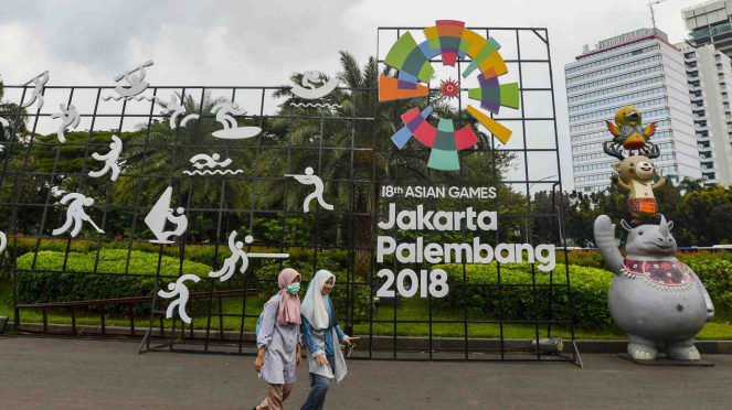 Warga berjalan di samping display promosi Asian Games 2018 di Jakarta