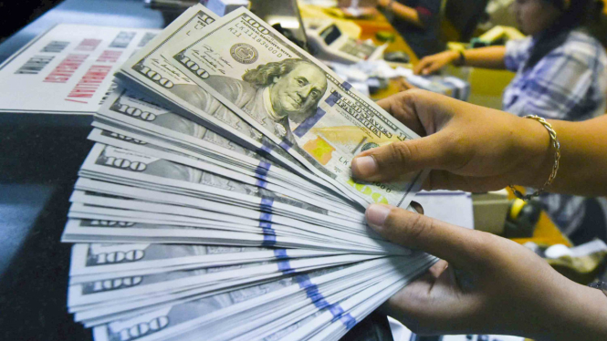 Petugas menghitung uang dolar Amerika Serikat di gerai penukaran mata uang asing