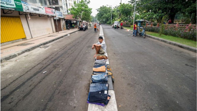 Seorang pedagang pakaian menggelar dagangannya di pembatas jalan Kota Surabaya, Oktober 2017 lalu. - AFP/Getty Images