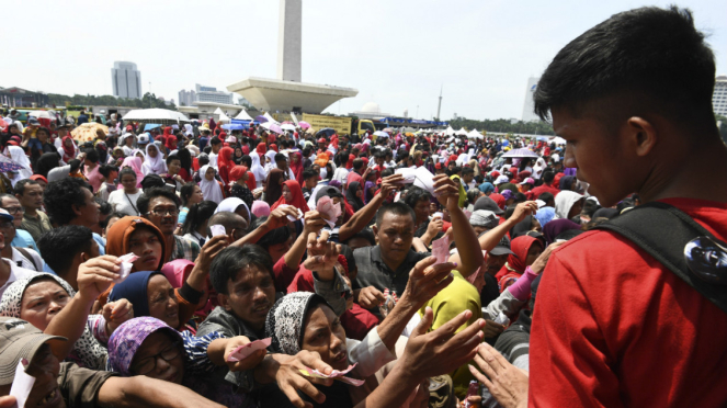 Sejumlah warga berdesakan untuk mengambil sembako gratis saat acara Untukmu Indonesia di kawasan Monas, Jakarta, Sabtu (28/4/2018). 