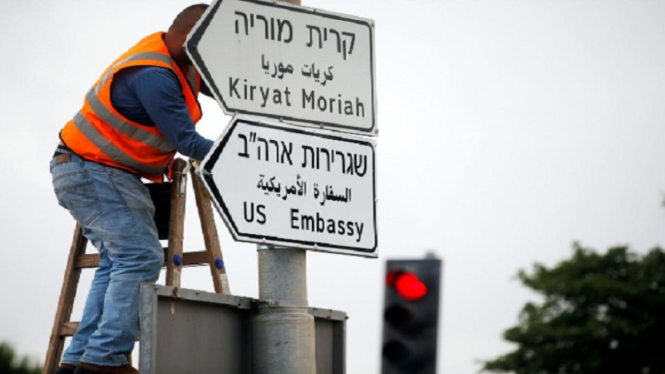 Seorang pekerja tengah memasang rambu menuju Kedutaan Besar AS di Yerusalem 