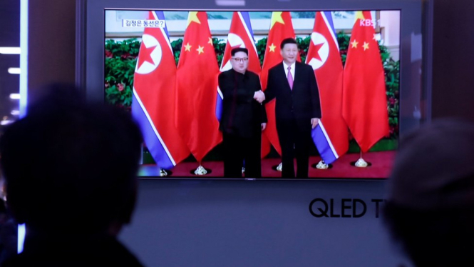 Warga Korea Selatan menyaksikan televisi yang menyiarkan berita tentang kunjungan Kim-Jong-un ke Cina. - Reuters