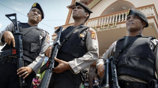 Tiga aparat bersenjata lengkap melakukan penjagaan sebuah gereja di Kota Banda Aceh, Minggu (13/05), tidak lama setelah serangan ledakan bom di Surabaya. - AFP/CHAIDEER MAHYUDDIN