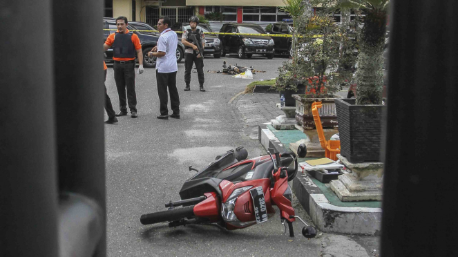 Petugas kepolisian berjaga di dekat jenazah pelaku penyerangan yang tergeletak di jalan pintu masuk Polda Riau di Pekanbaru