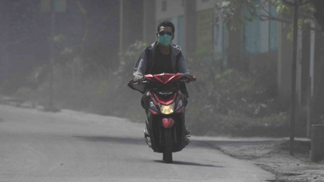 Pengendara sepeda motor mengenakan masker saat melintas di kawasan Gunung Merapi