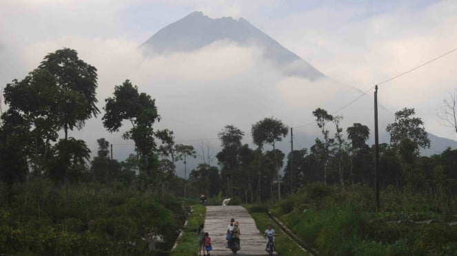 Sejumlah warga melintasi jalan pedesaan di sekitar Gunung Merapi